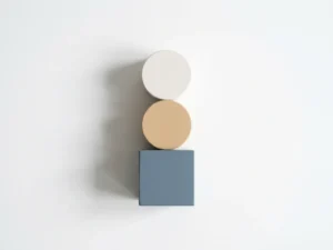 Geometrische Holzblöcke in Würfel-, Zylinder- und Scheibenform auf weißem Untergrund, Draufsicht, gedämpfte Farbtöne in Blau, Sand und Weiß.