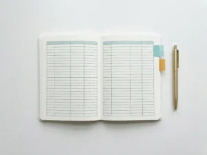 Ordentlich aufgelegtes Tabellenblatt mit farbigen Reitern in Türkis und Gold auf weißem Schreibtisch, daneben ein schlanker Stift.